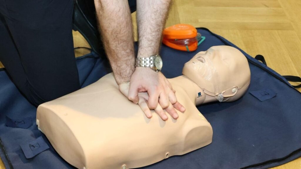 a man practicing cpr doing chest compressions on a dummy