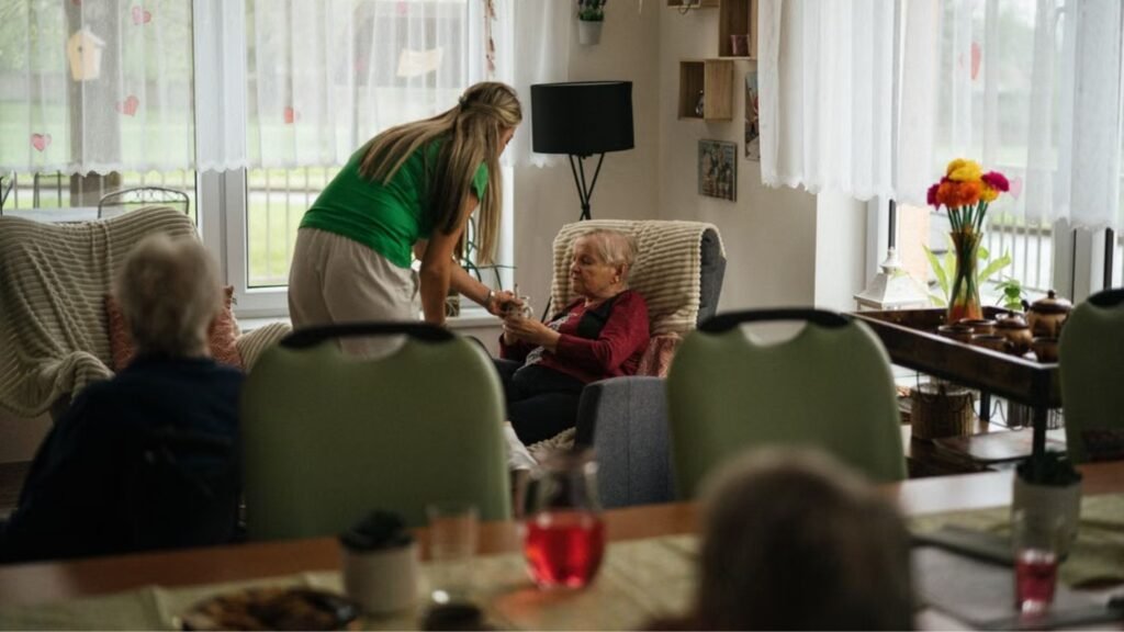 a woman handing a water to an elderly woman_Medication Aide Classes