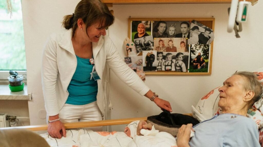 a woman talking with an elderly woman lying in bed